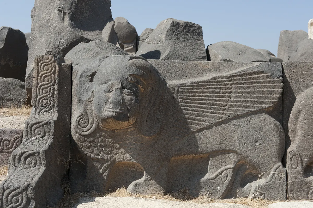 Ancient temple platform with carved basalt lions and giant footprints