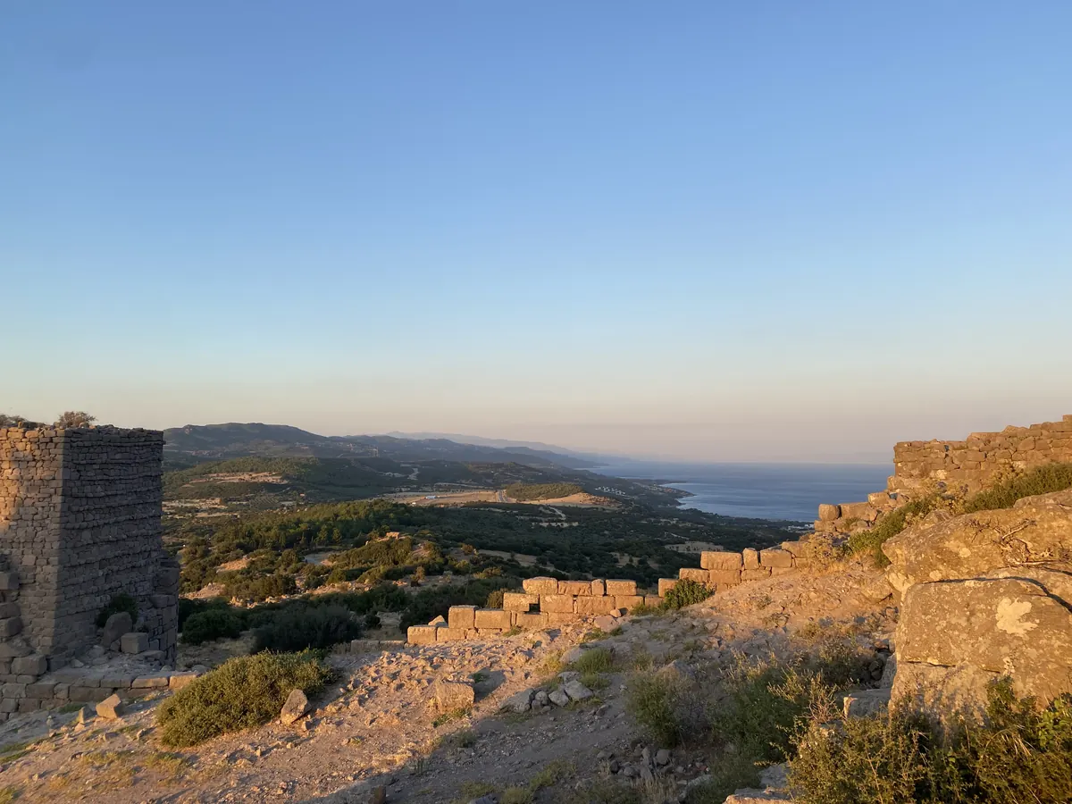 Grey Doric columns on a clifftop with the sea and Lesbos in the distance