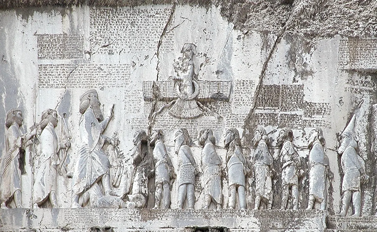 Rock relief of a Persian king before a line of bound prisoners, with cuneiform panels