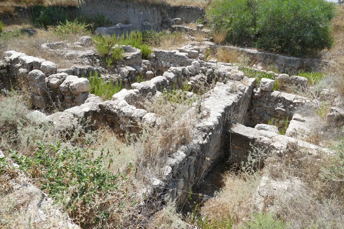 Excavated mound above a fertile valley with rock-cut reservoir opening