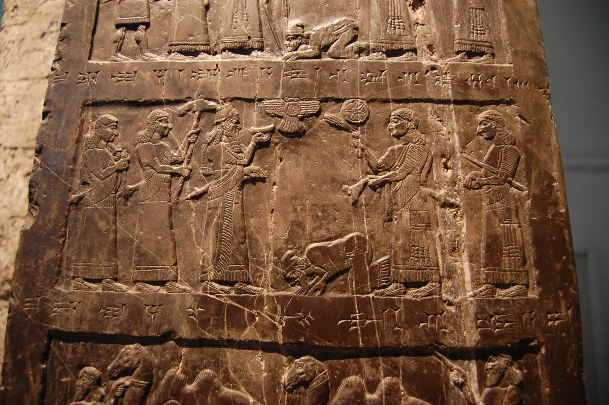 Carved relief of a kneeling king before a standing Assyrian monarch