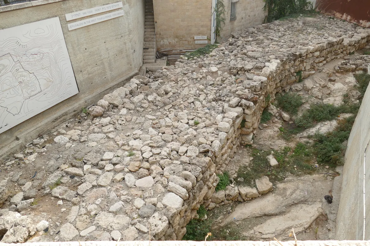 Thick line of large fieldstones exposed below modern buildings