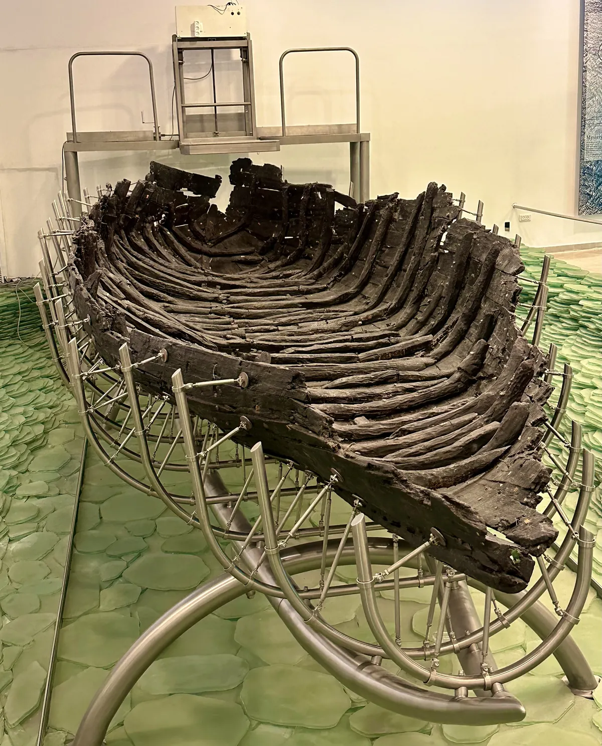 Dark ancient wooden boat hull displayed in a museum hall