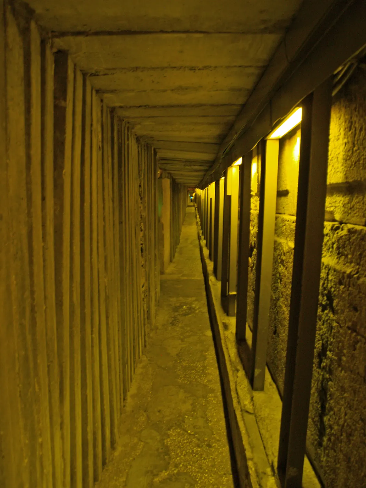 Narrow rock-cut water channel lit for visitors