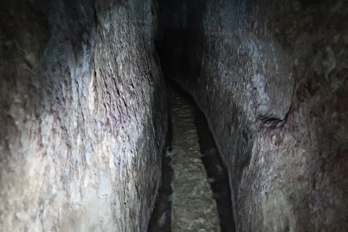 Narrow rock-cut tunnel with water on the floor