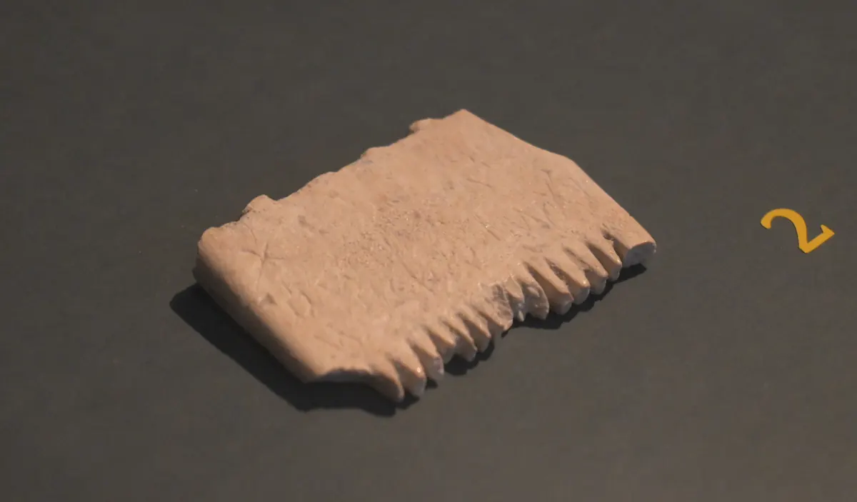 Small ivory comb with tiny scratched letters along its edge