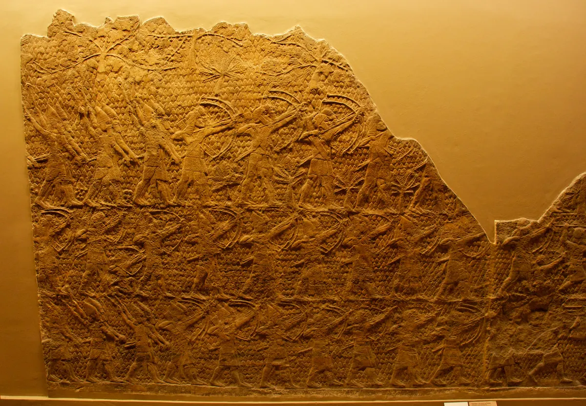 Carved stone panel with Assyrian soldiers attacking a walled city