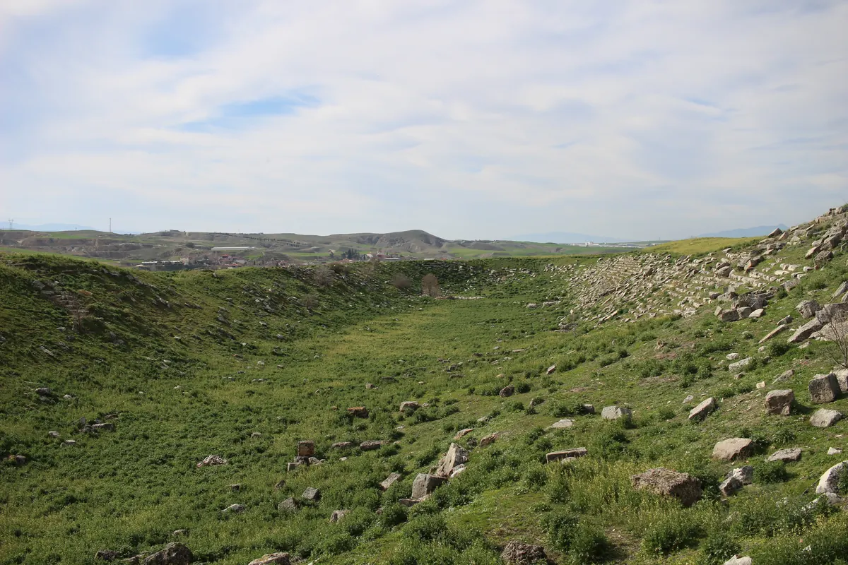 Long grassy hollow of an ancient stadium with scattered stone seats