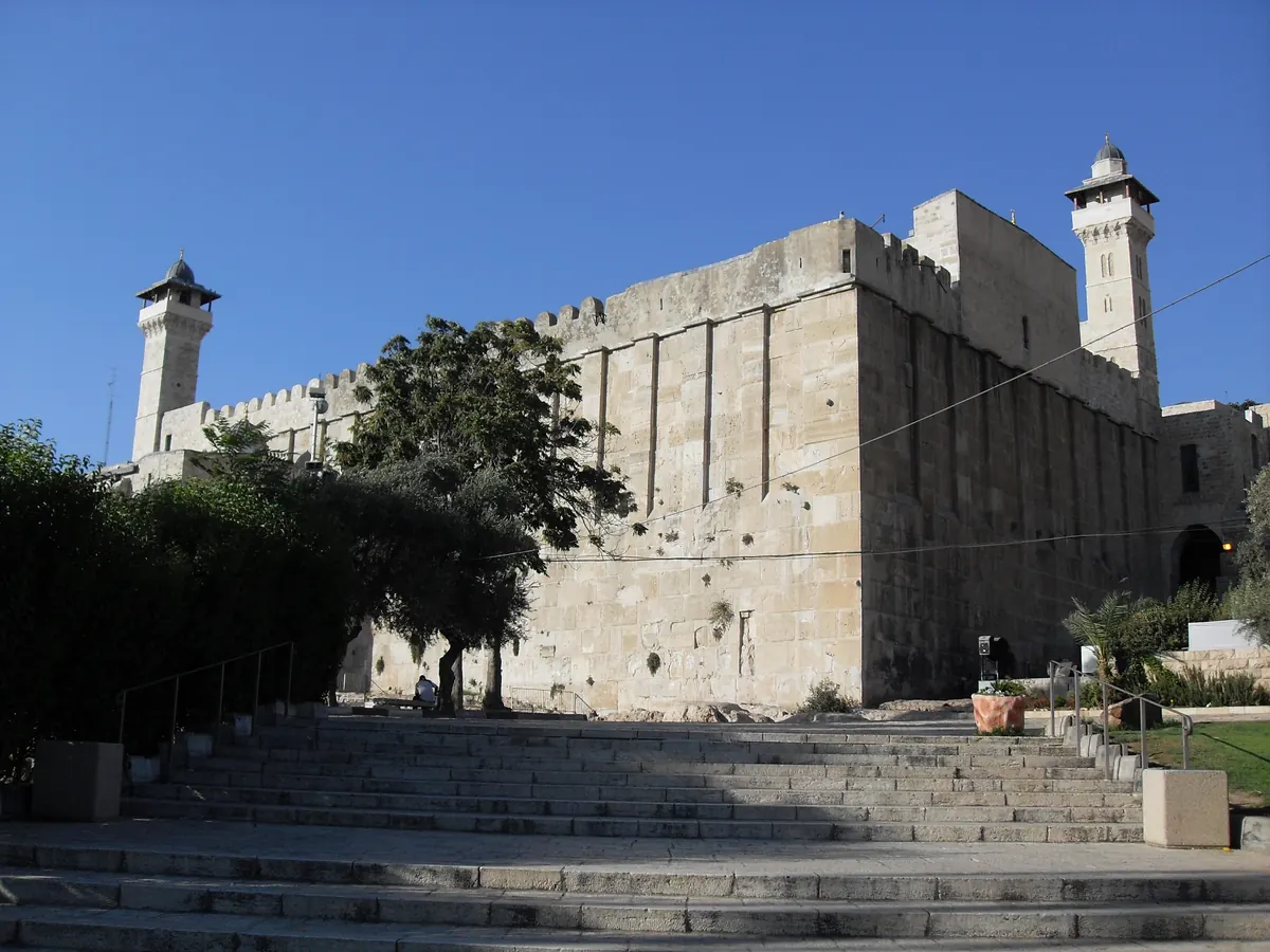 Large ancient stone building with massive ashlar walls and minarets