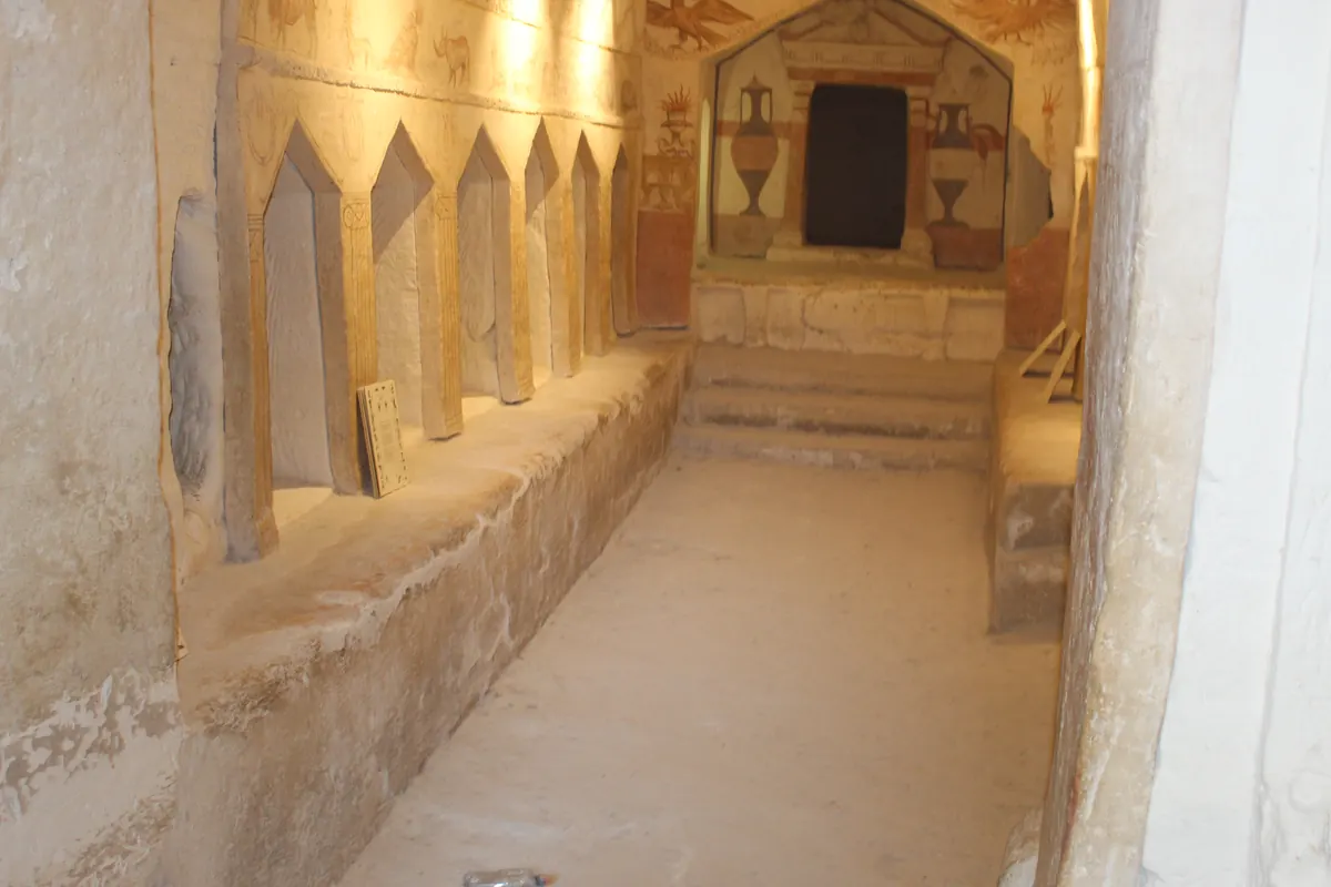 Rock-cut tomb hall with painted animals above burial niches