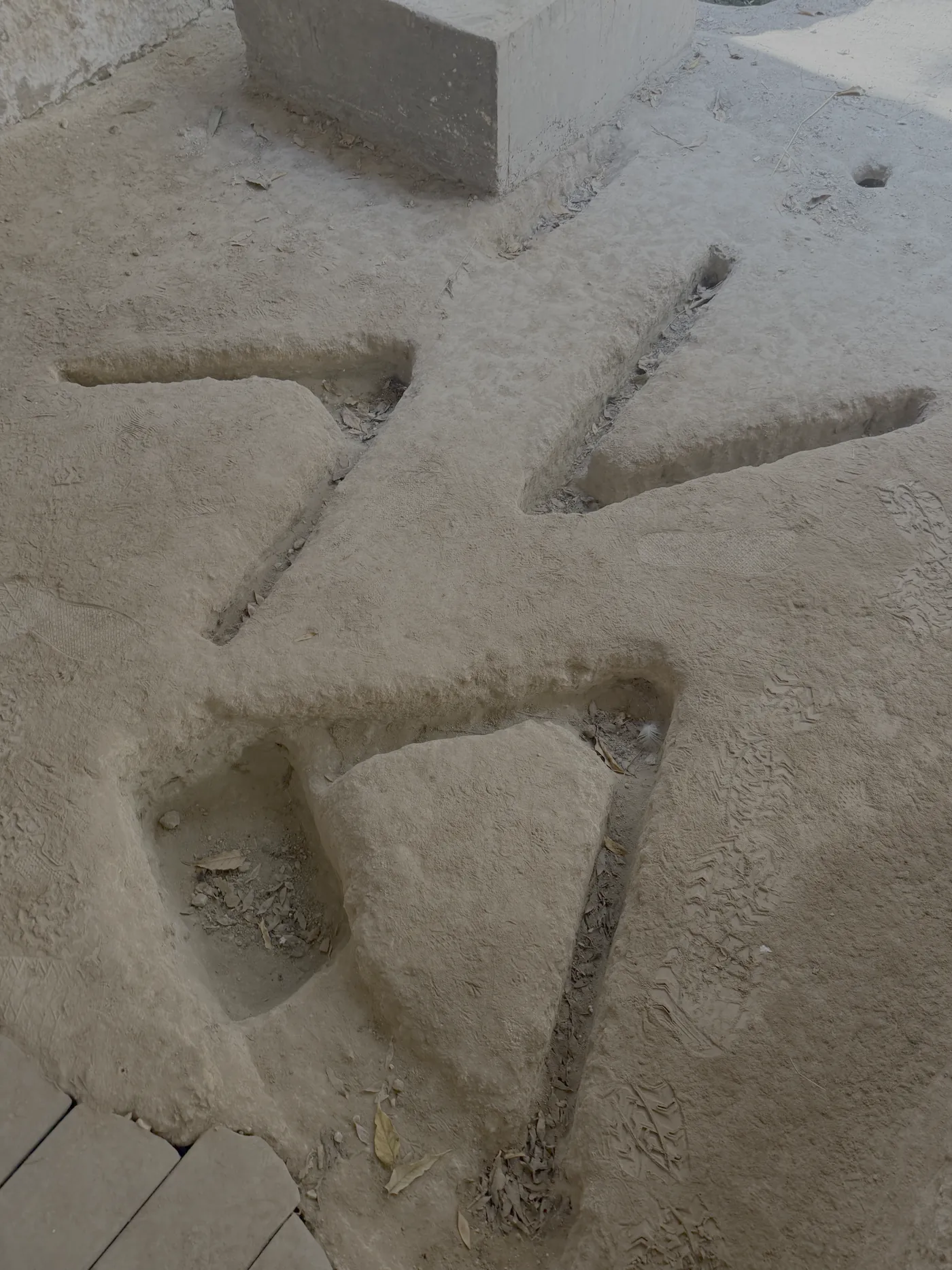 The V-shaped grooves cut into the bedrock floor, with a basin beside them