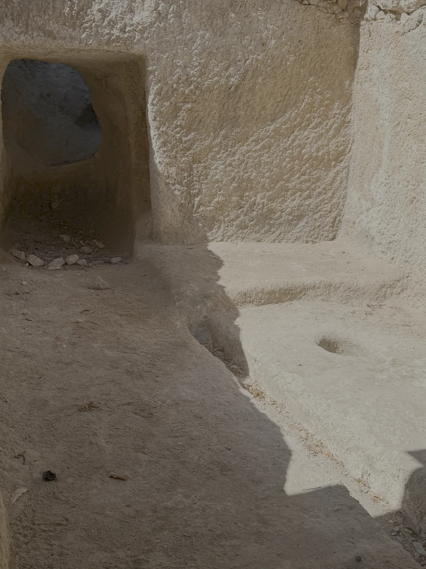 A rock-cut room with its channel and pressing basin; the doorway leads to the next chamber