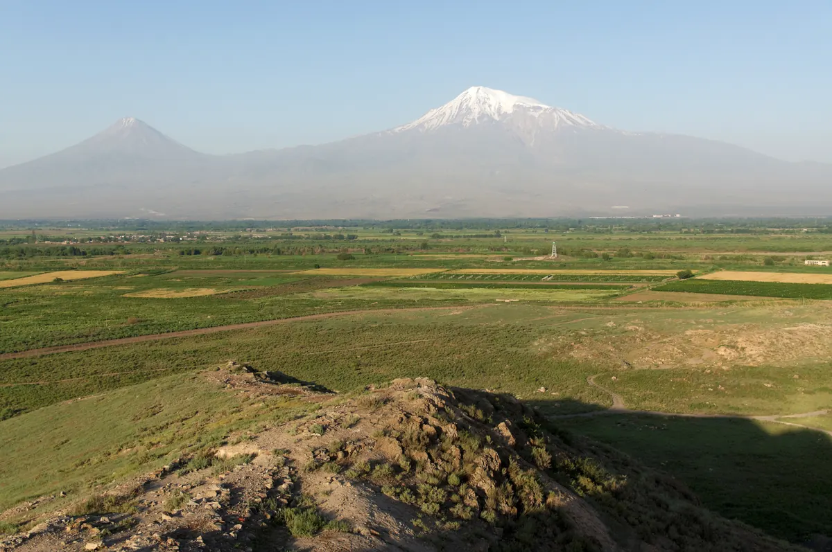 Snow-capped volcanic mountain rising above a plain