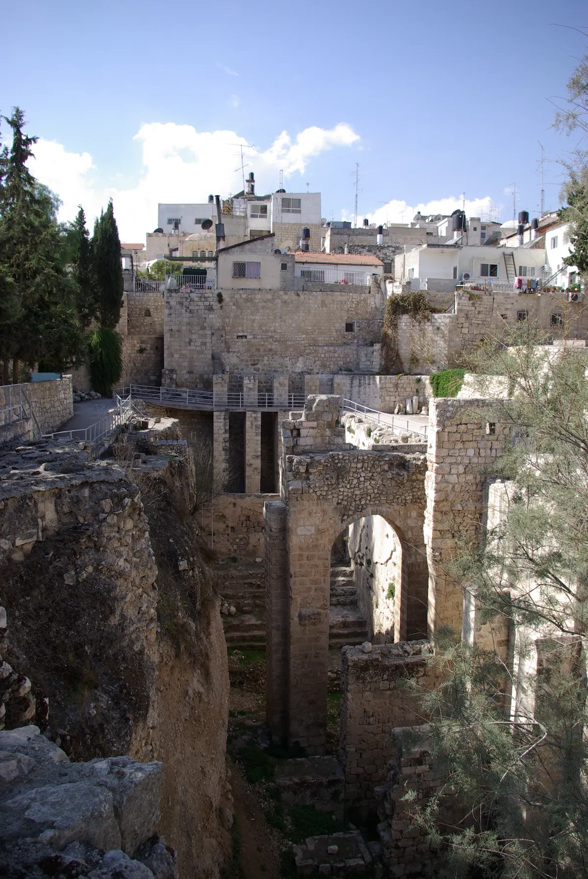 Deep rock-cut pool ruins with later church arches