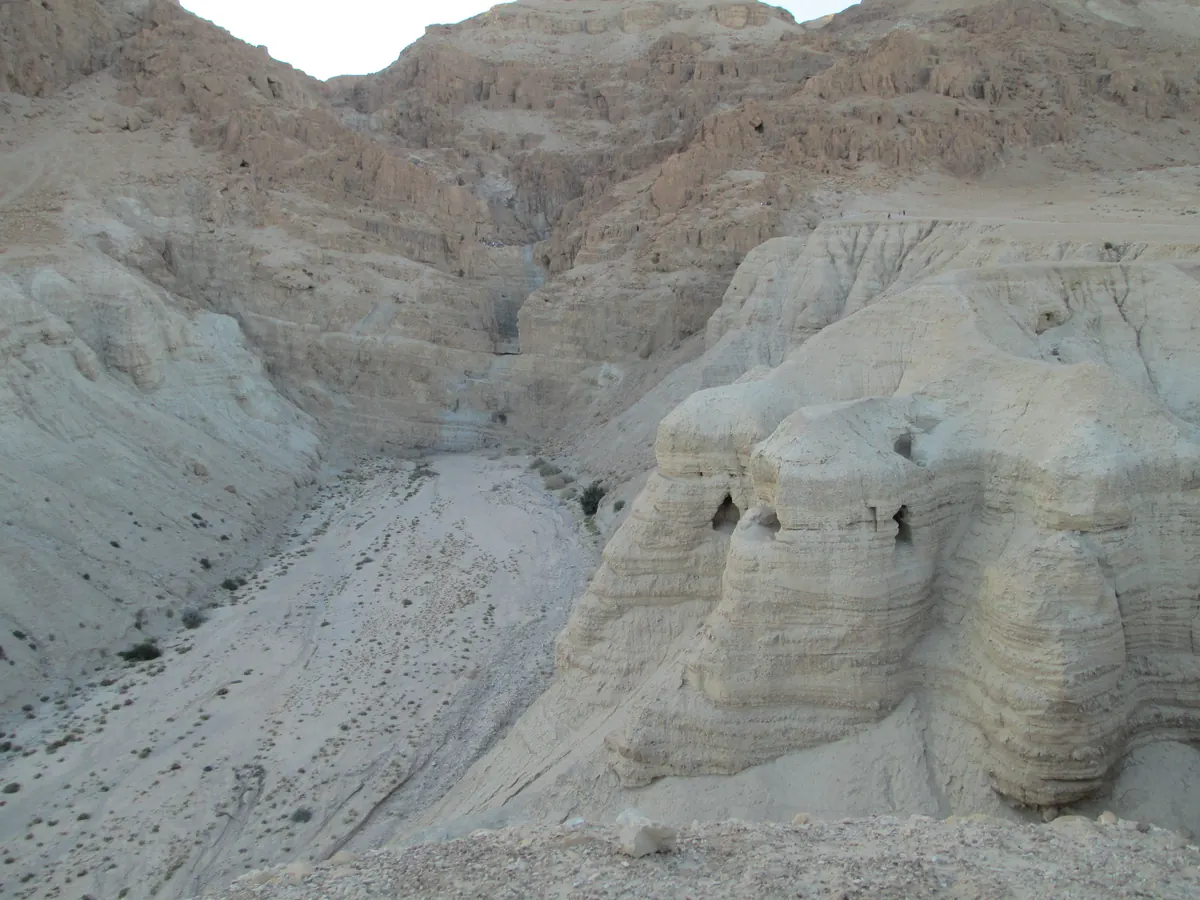 Narrow cave entrance in a desert cliff with excavation equipment