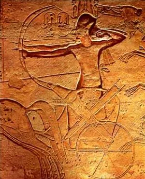 Carved relief of a pharaoh in a chariot attacking enemies