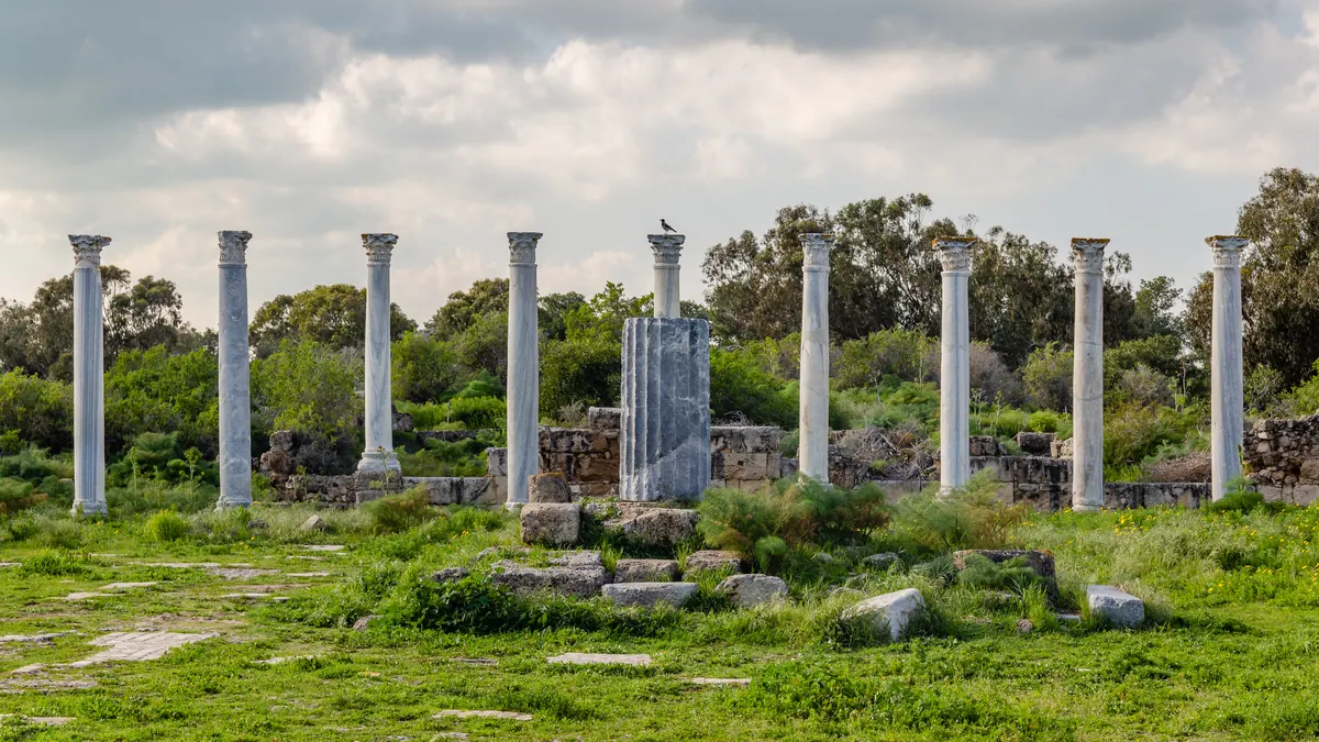Rows of white marble columns around a paved courtyard with headless statues
