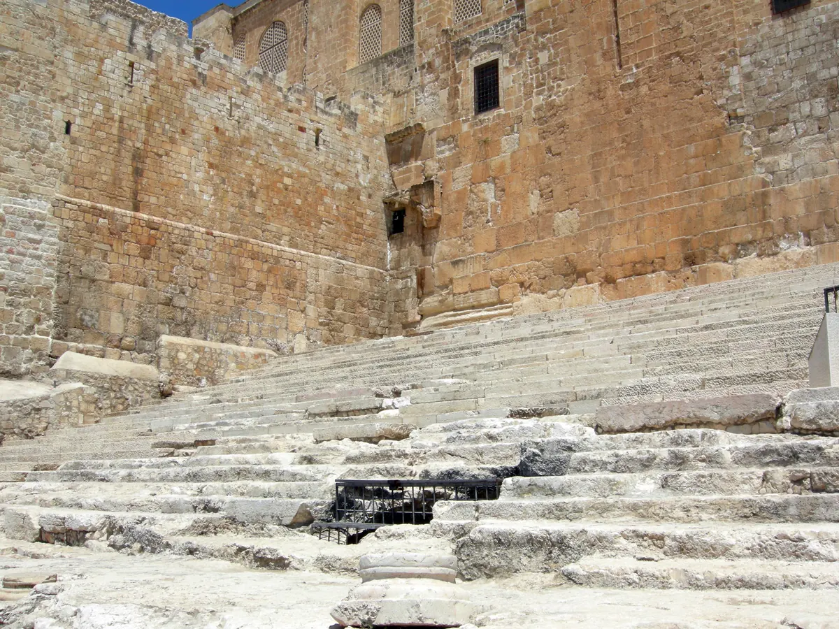 Broad ancient stone staircase leading up to a blocked gate in a massive wall